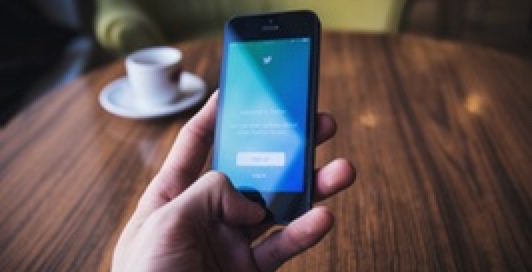 Someone holding a mobile phone and another drinking coffee